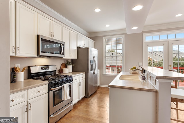 kitchen with appliances with stainless steel finishes, sink, a kitchen breakfast bar, crown molding, and a center island with sink