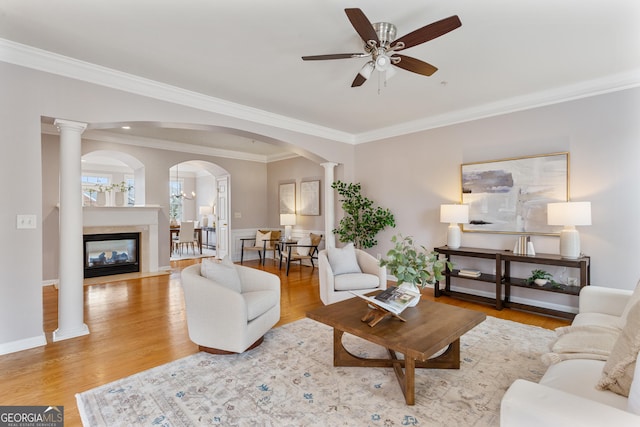 living room with light hardwood / wood-style flooring, ornamental molding, ceiling fan, and ornate columns