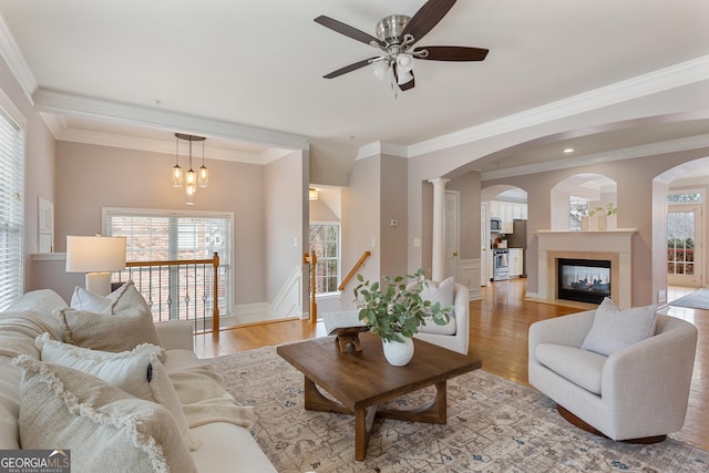 living room featuring crown molding, a tiled fireplace, and light hardwood / wood-style flooring