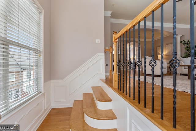 stairway with ornamental molding and hardwood / wood-style floors