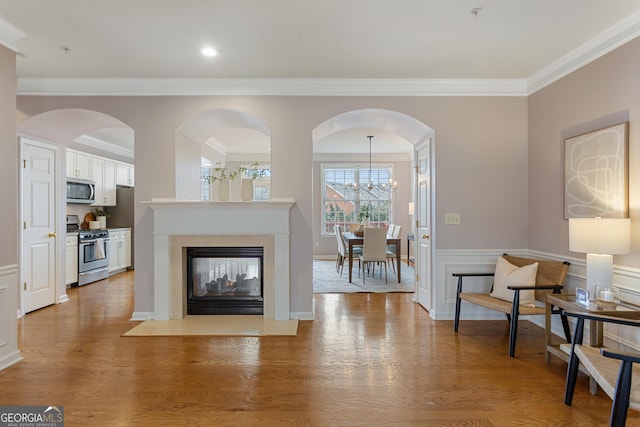 living room with ornamental molding, hardwood / wood-style floors, a multi sided fireplace, and a chandelier