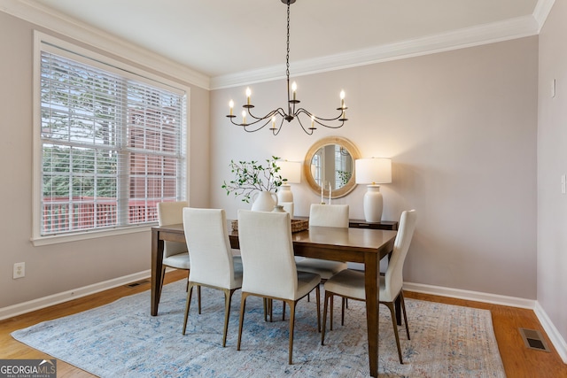 dining room with hardwood / wood-style flooring, ornamental molding, and a notable chandelier