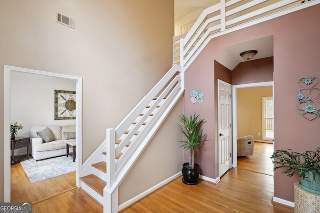 stairs featuring wood-type flooring and a high ceiling