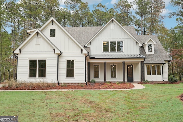 modern farmhouse style home featuring a standing seam roof, a front yard, board and batten siding, and roof with shingles