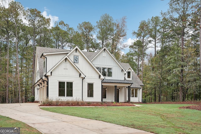 modern inspired farmhouse with a standing seam roof, board and batten siding, concrete driveway, and a front lawn