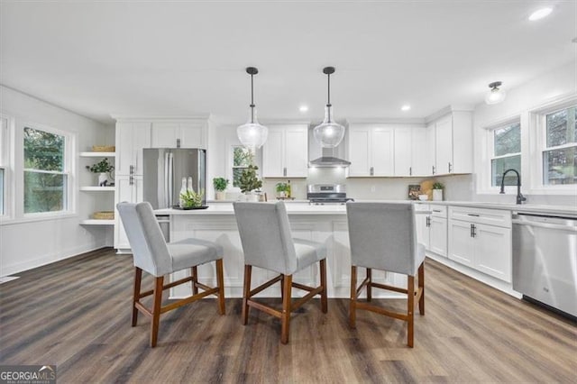 kitchen featuring pendant lighting, sink, white cabinets, a center island, and stainless steel appliances