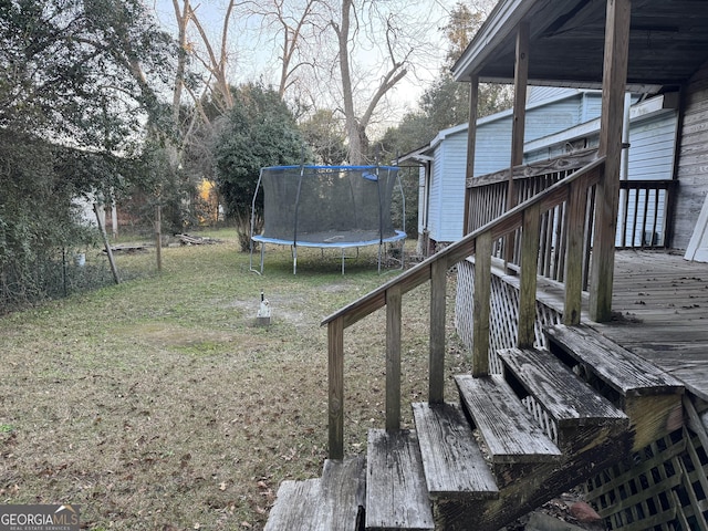 view of yard featuring a wooden deck and a trampoline