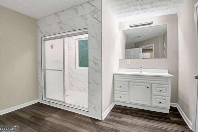 bathroom with vanity, hardwood / wood-style floors, a textured ceiling, and a tile shower