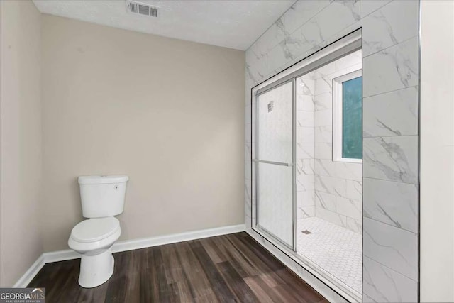 bathroom featuring wood-type flooring, toilet, and an enclosed shower