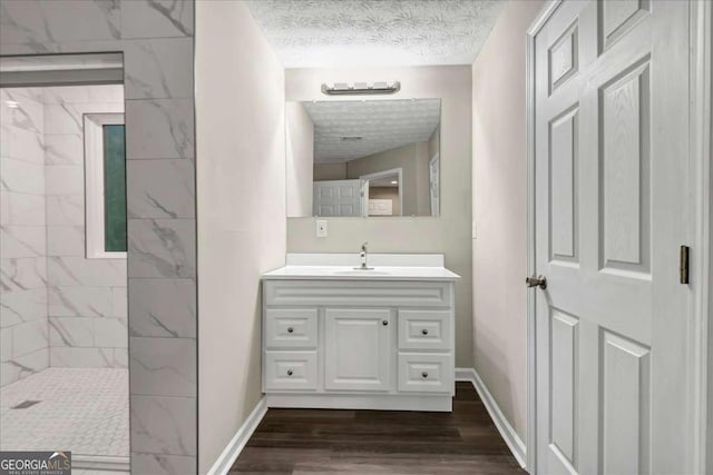 bathroom with vanity, wood-type flooring, a textured ceiling, and tiled shower