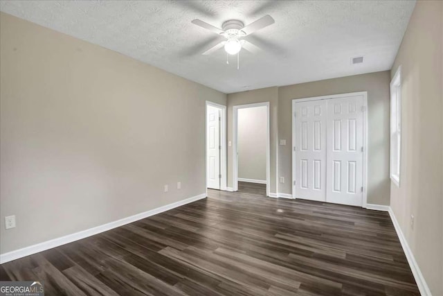 unfurnished bedroom featuring multiple windows, ceiling fan, dark hardwood / wood-style flooring, and a textured ceiling