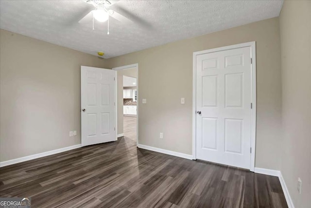 unfurnished bedroom featuring dark hardwood / wood-style flooring, a textured ceiling, and ceiling fan