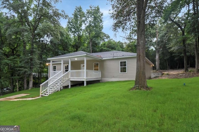 rear view of house featuring a porch and a yard