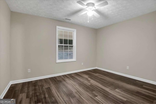 spare room featuring ceiling fan, dark wood-type flooring, and a textured ceiling