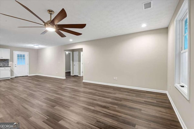 unfurnished living room featuring dark wood-type flooring, a wealth of natural light, and ceiling fan