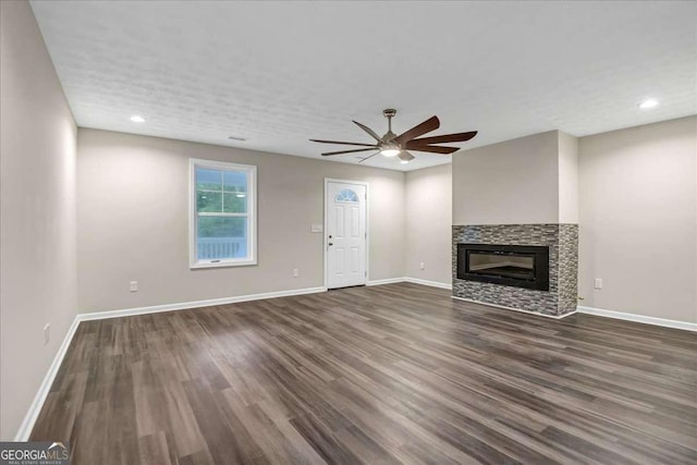 unfurnished living room featuring dark wood-type flooring and ceiling fan