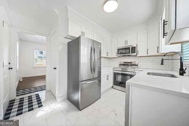 kitchen with sink, white cabinetry, stainless steel appliances, light stone counters, and tasteful backsplash