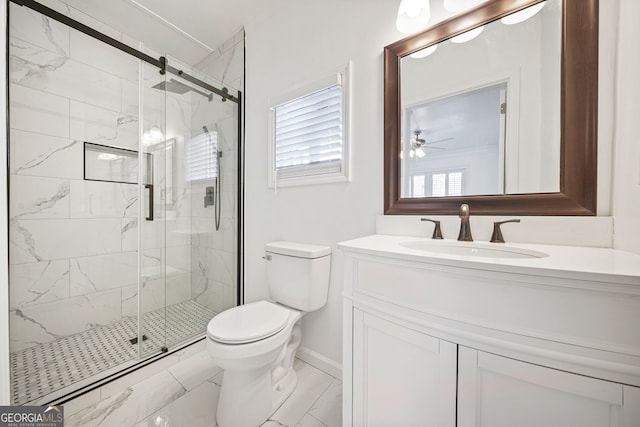 bathroom featuring vanity, ceiling fan, a shower with door, and toilet