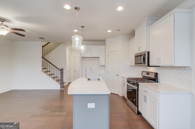 kitchen with sink, white cabinetry, stainless steel appliances, tasteful backsplash, and an island with sink