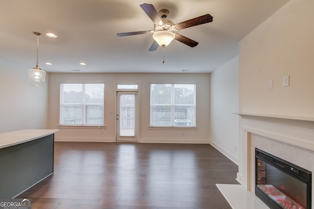 unfurnished living room featuring ceiling fan, dark hardwood / wood-style flooring, and a wealth of natural light