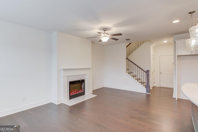 unfurnished living room with a premium fireplace, ceiling fan, and dark hardwood / wood-style flooring