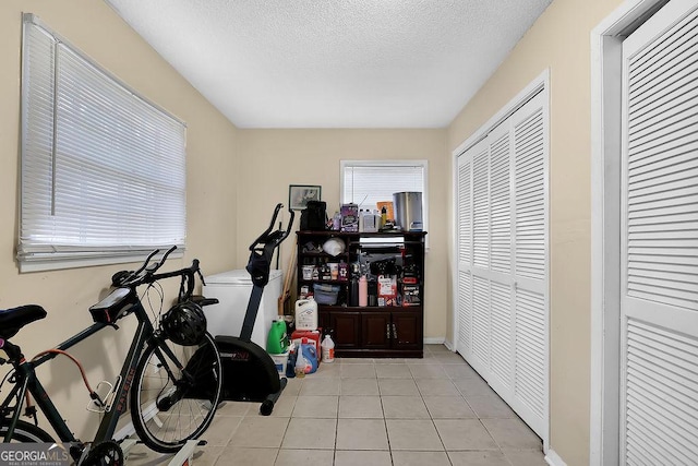 exercise area featuring light tile patterned floors and a textured ceiling