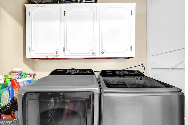 washroom featuring cabinets and washer and clothes dryer