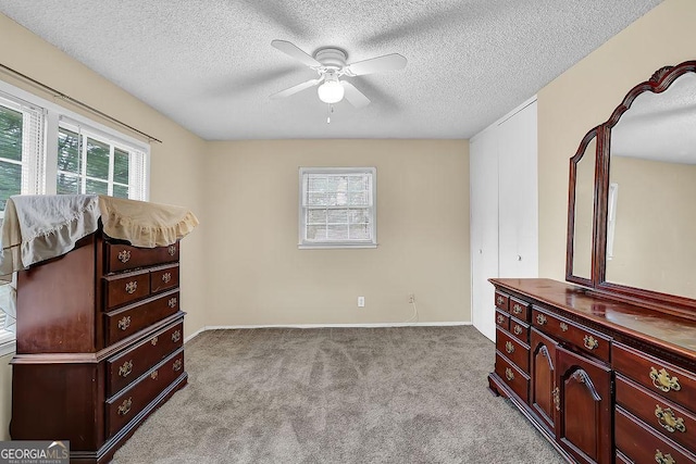 bedroom featuring ceiling fan, light colored carpet, and a textured ceiling