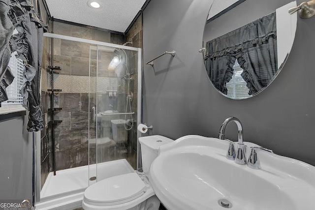 bathroom featuring toilet, sink, a textured ceiling, and a shower with shower door