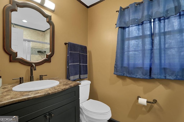 bathroom with ornamental molding, vanity, and toilet