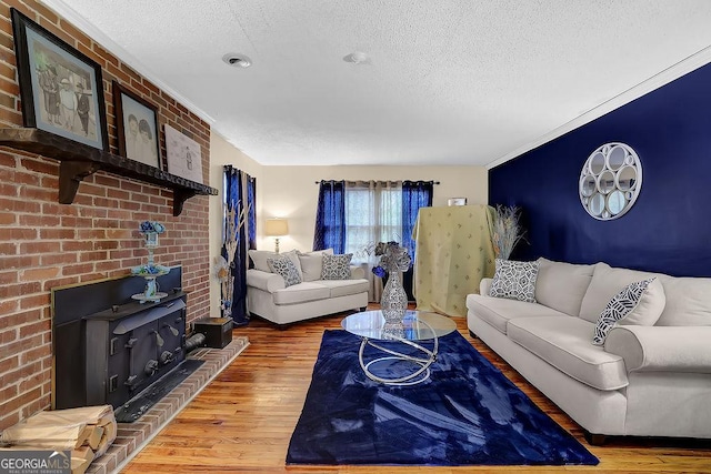 living room with wood-type flooring, a wood stove, and a textured ceiling