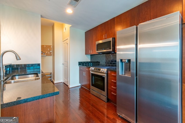 kitchen with appliances with stainless steel finishes, dark hardwood / wood-style floors, sink, and backsplash