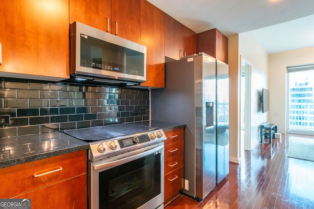 kitchen featuring tasteful backsplash, stainless steel appliances, wood-type flooring, and dark stone counters