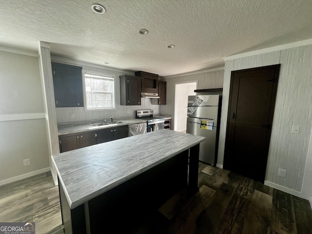 kitchen with dark wood-type flooring, sink, a textured ceiling, appliances with stainless steel finishes, and a kitchen island