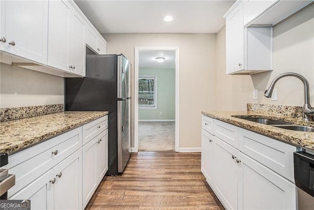 kitchen with white cabinetry, sink, light hardwood / wood-style floors, stainless steel appliances, and light stone countertops