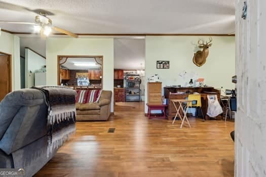 living room featuring ceiling fan, wood-type flooring, and a textured ceiling