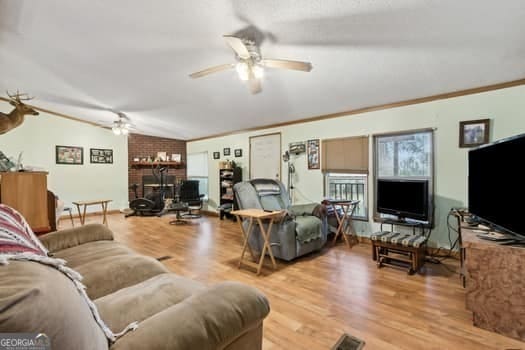 living room with crown molding, ceiling fan, wood-type flooring, and vaulted ceiling