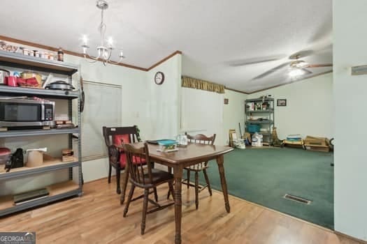 dining area with crown molding, hardwood / wood-style flooring, and ceiling fan with notable chandelier