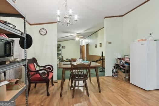 dining space with hardwood / wood-style flooring, ceiling fan with notable chandelier, and ornamental molding