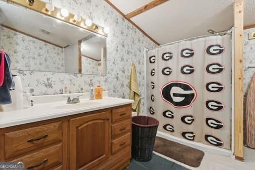 bathroom featuring vanity, lofted ceiling, and a shower with shower curtain