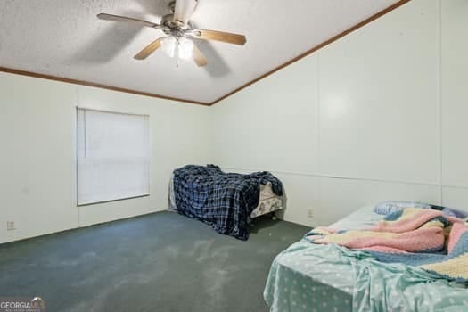 bedroom featuring vaulted ceiling, dark colored carpet, ornamental molding, ceiling fan, and a textured ceiling