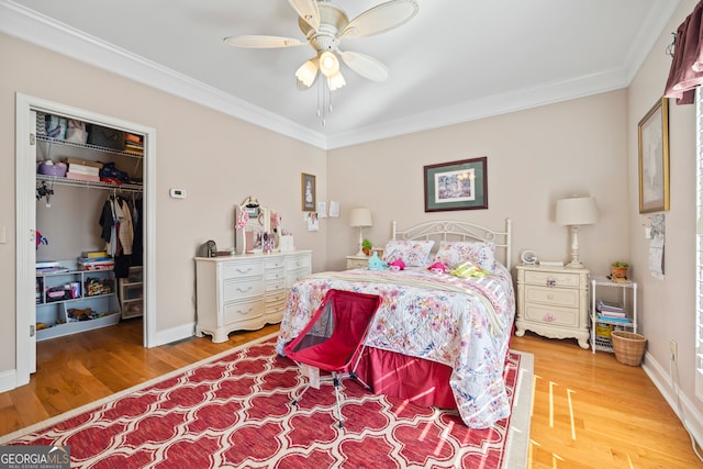 bedroom with hardwood / wood-style flooring, crown molding, ceiling fan, and a closet