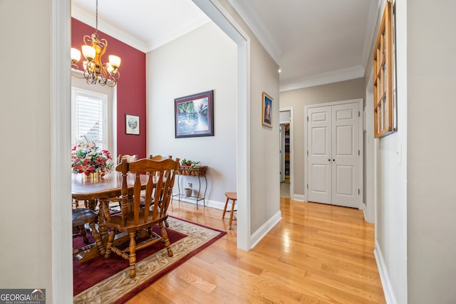 dining area with crown molding, light wood-type flooring, and a chandelier