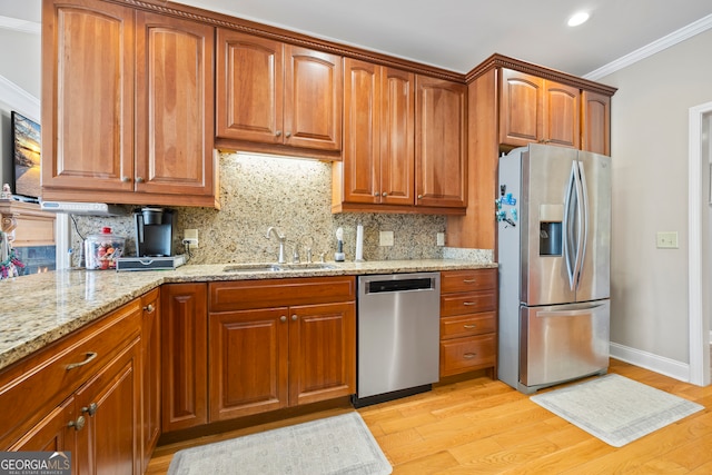 kitchen with sink, light stone counters, crown molding, stainless steel appliances, and light hardwood / wood-style floors