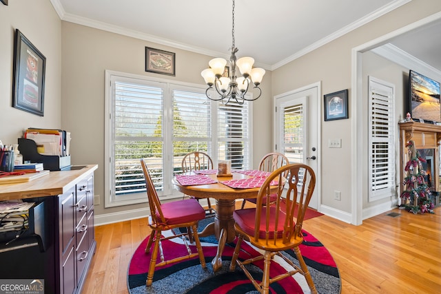 dining area featuring an inviting chandelier, ornamental molding, and light wood-type flooring