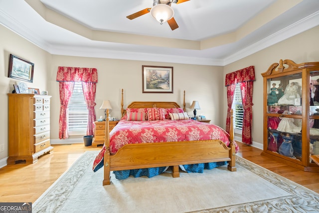 bedroom featuring a raised ceiling, ceiling fan, and light wood-type flooring