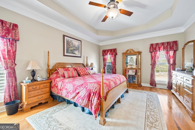 bedroom with a tray ceiling, ceiling fan, and light wood-type flooring