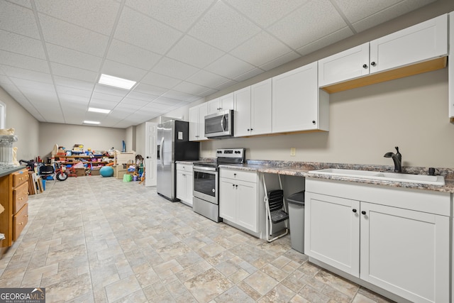 kitchen featuring appliances with stainless steel finishes, sink, a paneled ceiling, and white cabinets