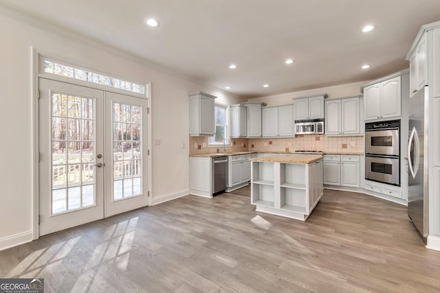 kitchen featuring a kitchen island, tasteful backsplash, white cabinetry, stainless steel appliances, and french doors