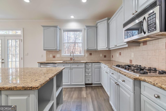 kitchen featuring light stone counters, sink, crown molding, and stainless steel appliances